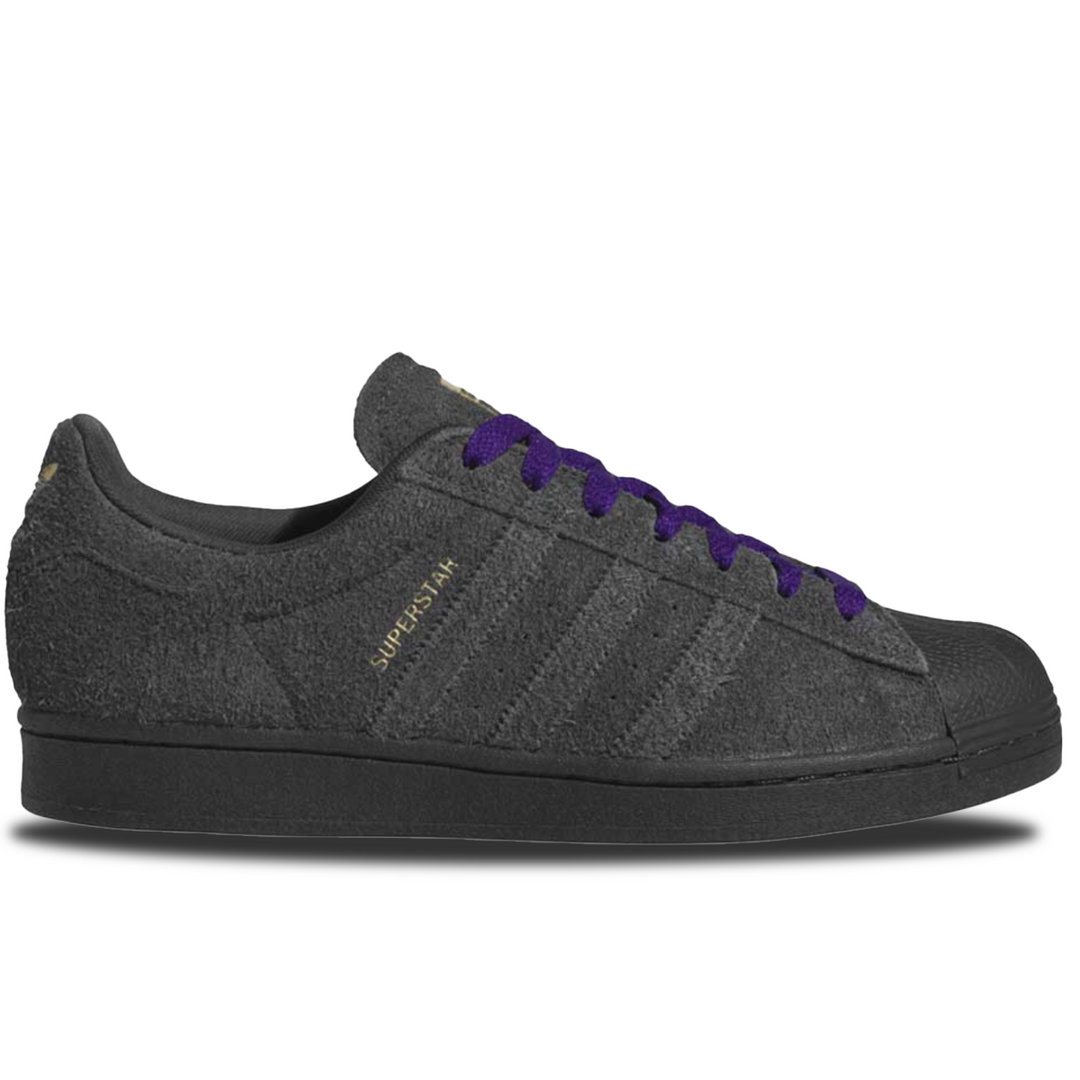 Dark gray Adidas Superstar sneaker with purple laces on a white background