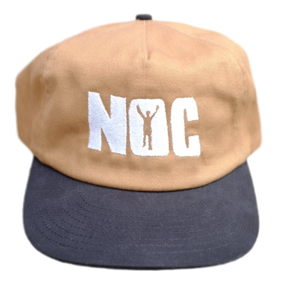 Two-tone cap with beige top and navy bottom, featuring 'NOC' logo on a white background