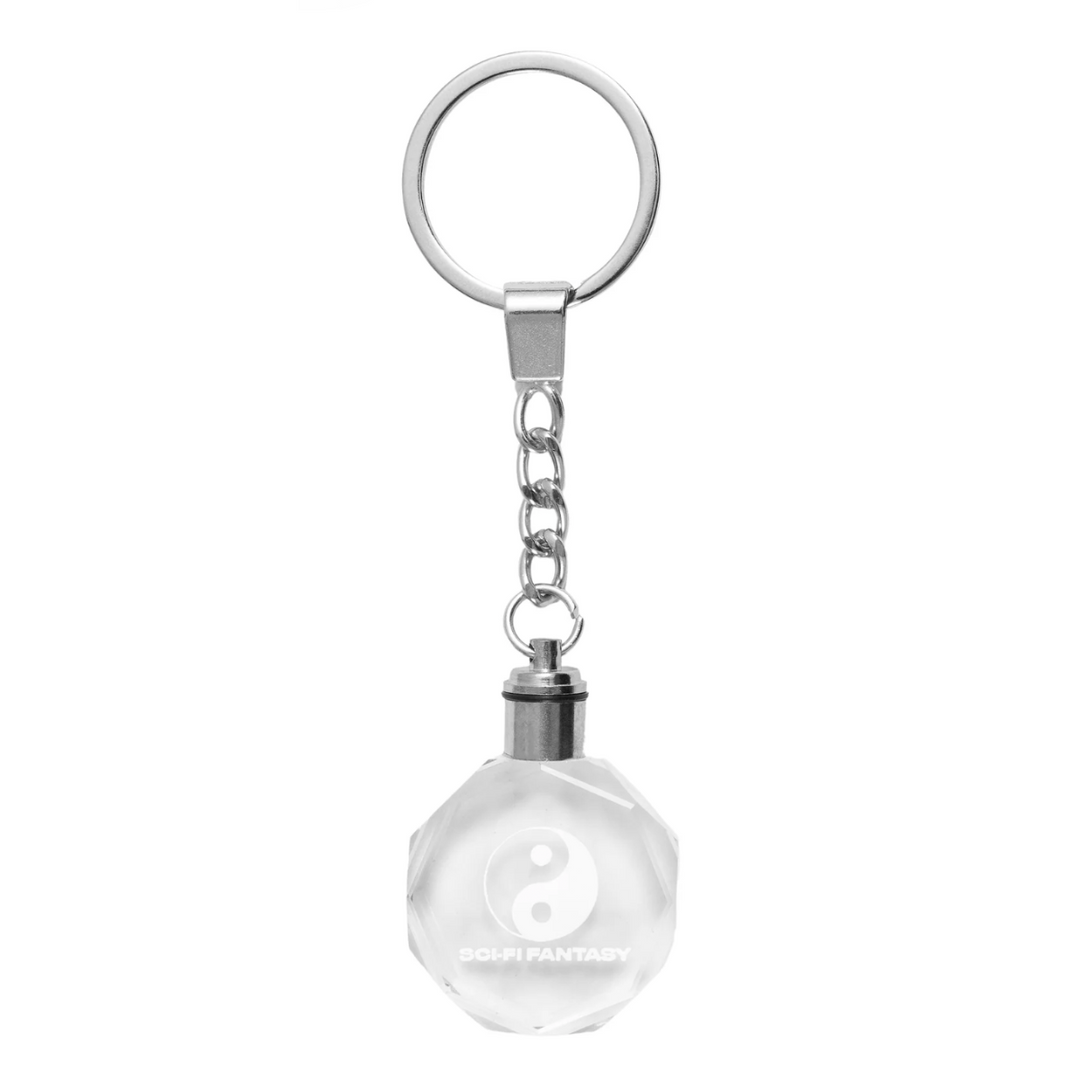 Keychain with a clear glass ball and yin yang symbol on a white background