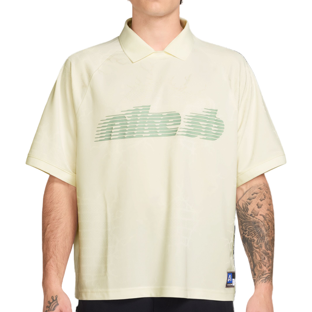 Man wearing a light-colored polo shirt with a green logo on a white background
