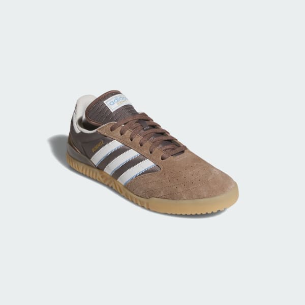 Brown Adidas sneaker with white stripes on a light gray background
