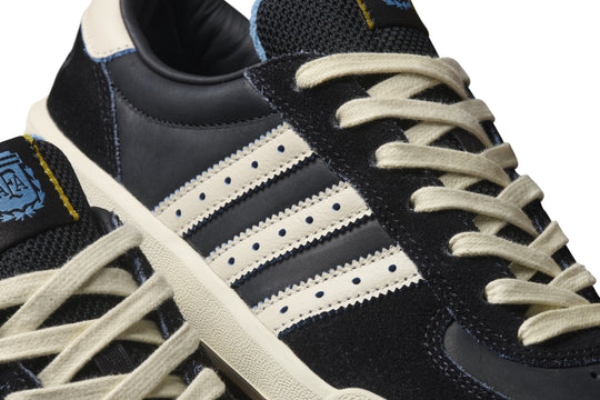 Close-up of black Adidas sneakers with white laces and stripes on a white background