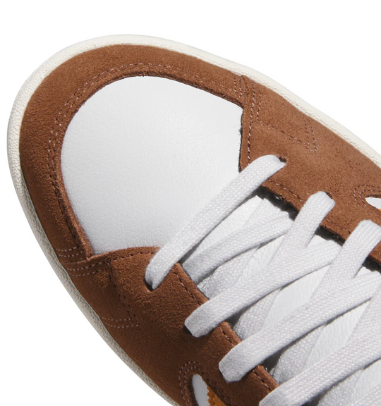 Close-up of a brown and white sneaker with white laces on a white background