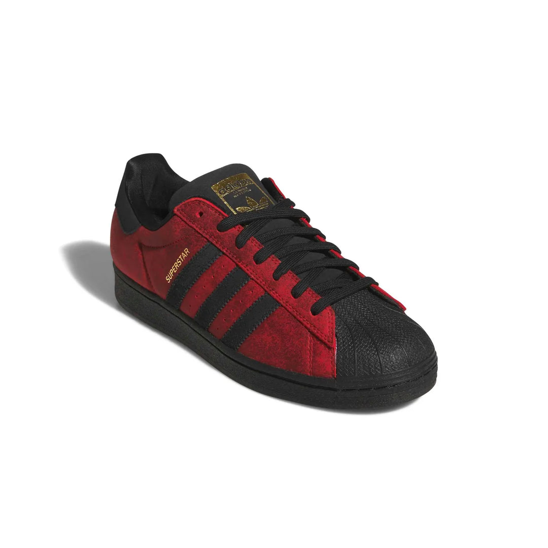 A red and black Adidas Superstar sneaker with gold branding details, shown from a three-quarters angle on a white background.