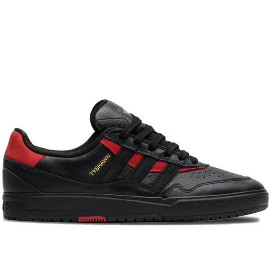A black leather low-top sneaker with red side stripes and heel tab, featuring gold &