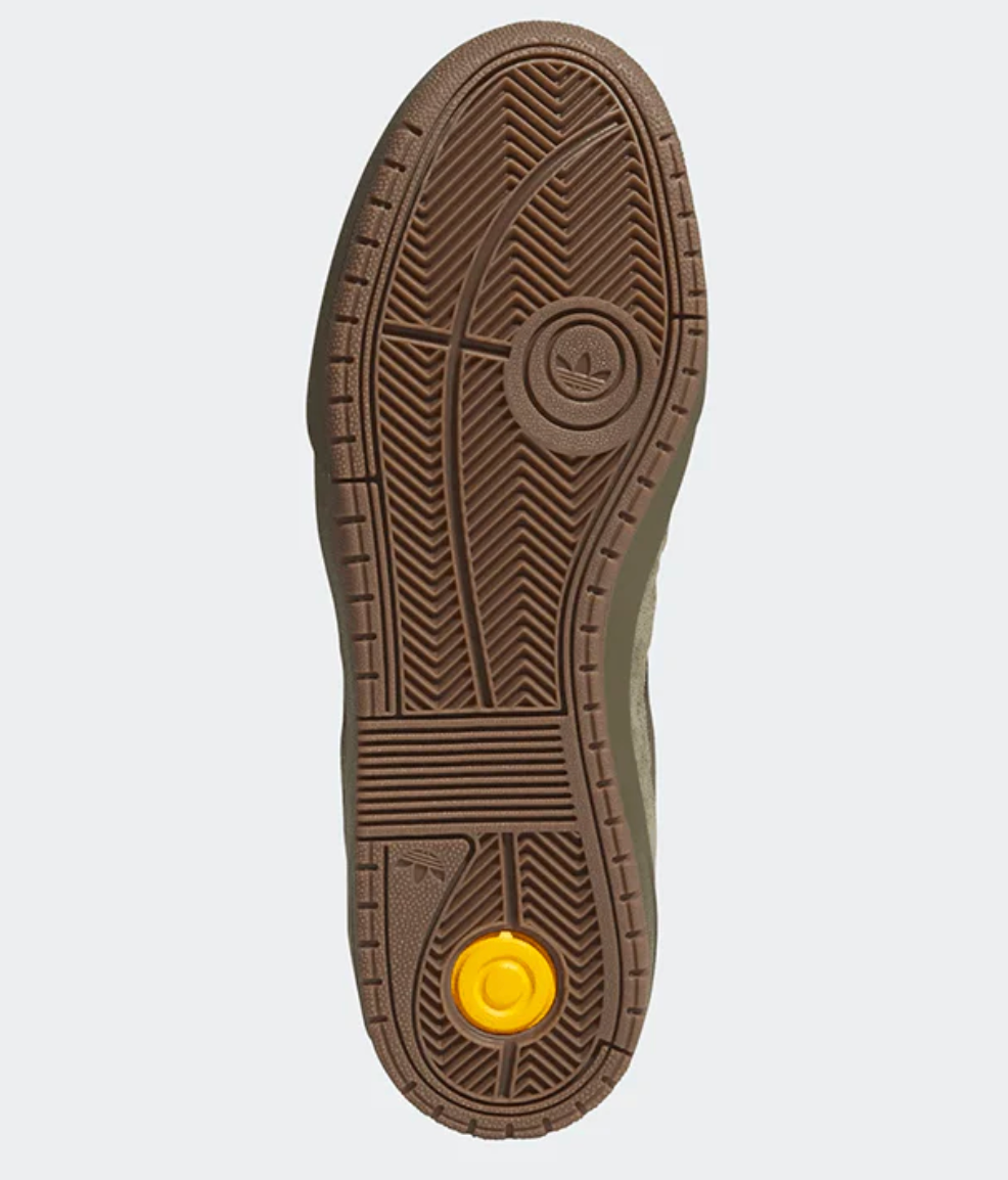 Close-up of a brown shoe sole with a yellow circular logo on a light gray background