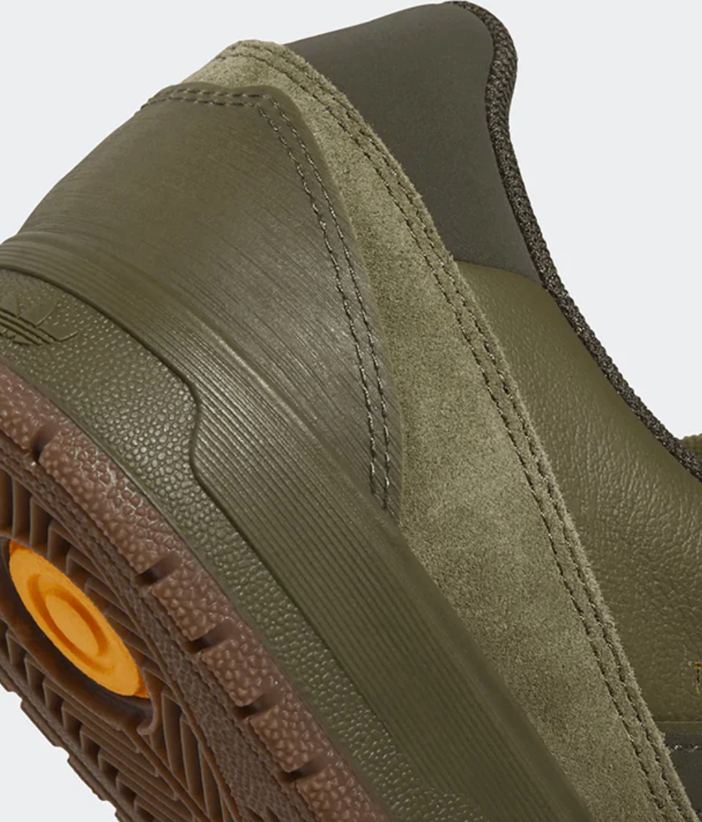 Close-up of a green slip-on shoe with brown sole on a white background