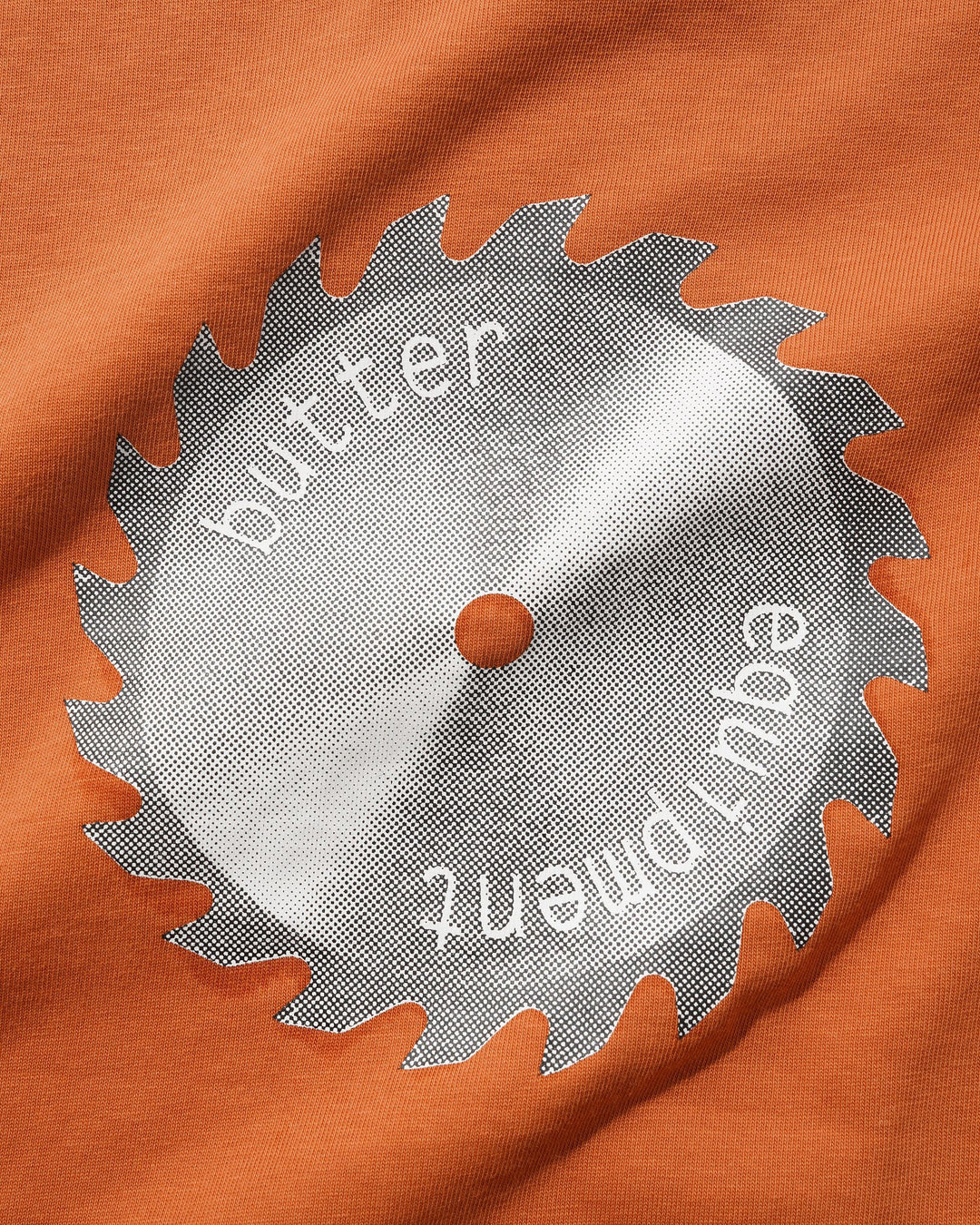 Saw blade with 'butter equipment' text on an orange fabric background