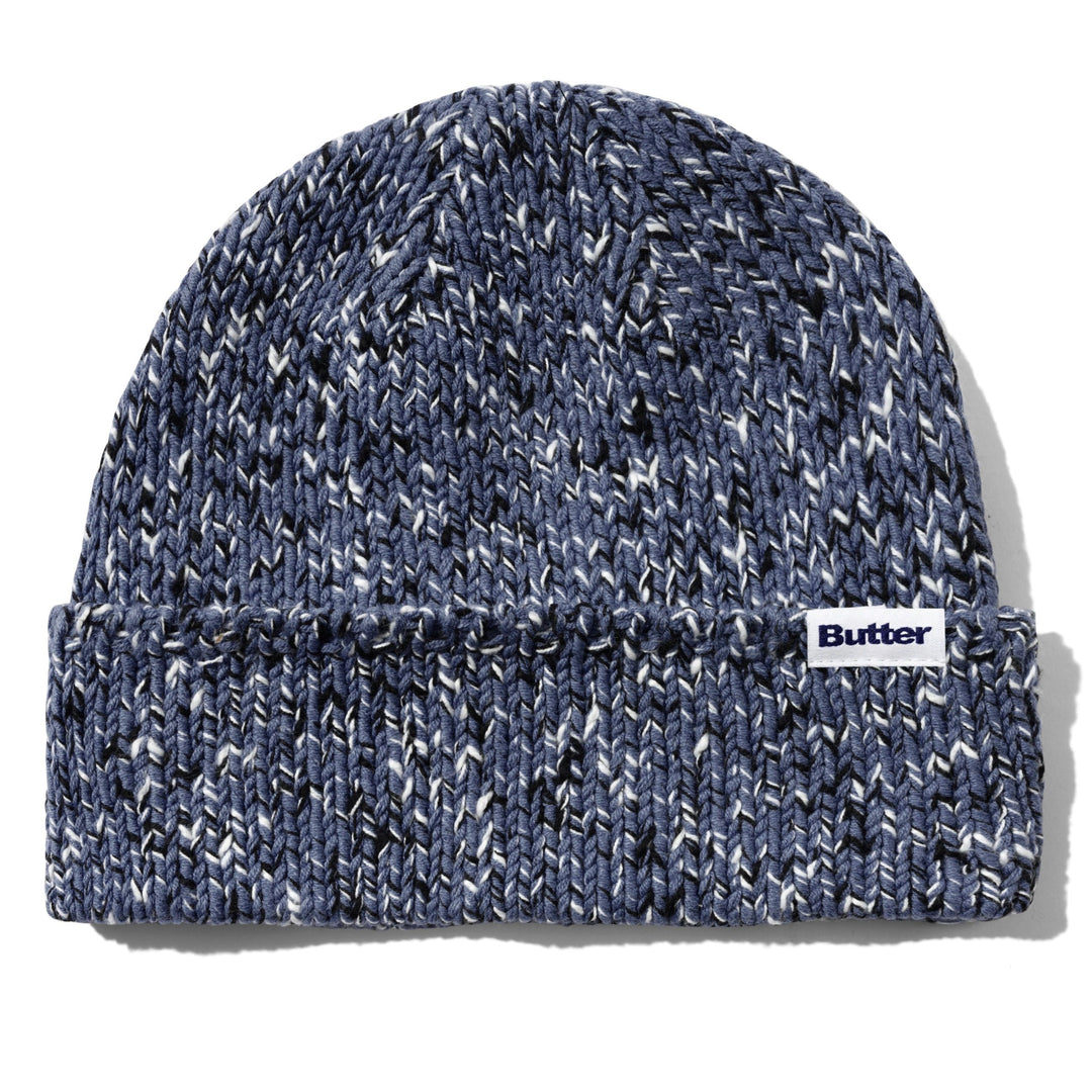 A navy blue and white marled knit beanie hat with a folded cuff, featuring a small white 'Butter' brand label on the side, set against a plain white background.