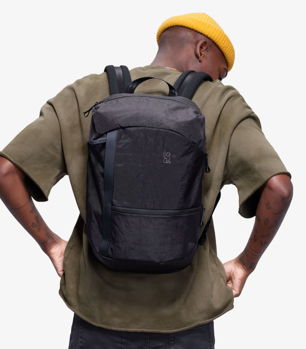 Person wearing a black backpack with a plain background