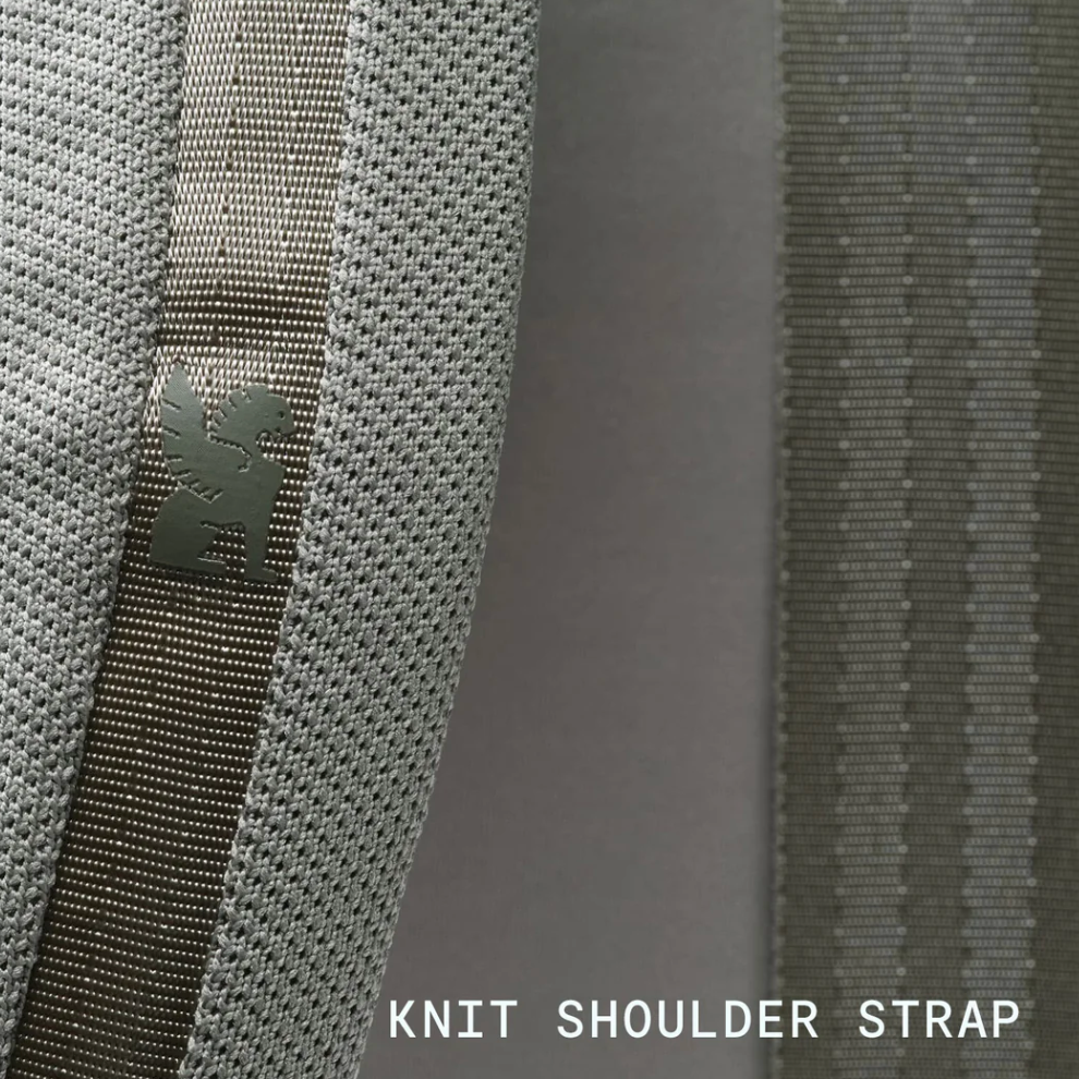 Close-up of a knit shoulder strap with a brand logo on a gray background