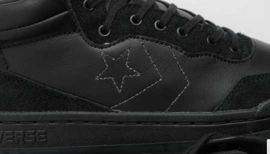 Black Converse sneaker with star logo on a gray background