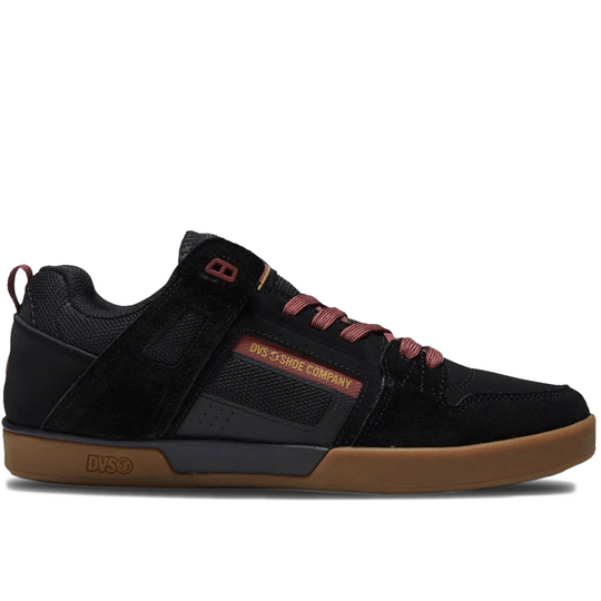 A black low-top skate shoe from DVS, featuring a suede and mesh upper, black laces with red tips, a red side logo, and a brown gum sole.