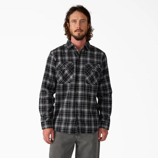 Man wearing a black and gray plaid shirt on a white background