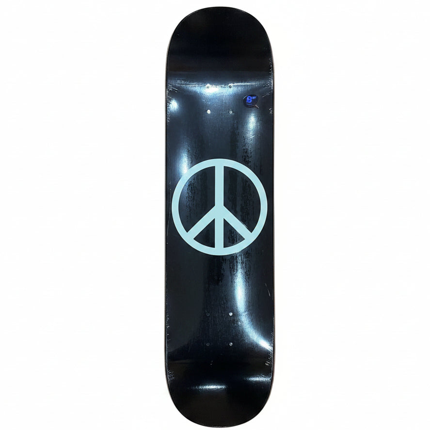 A black skateboard deck with a large white peace sign graphic in the center, photographed from above on a light wood floor.