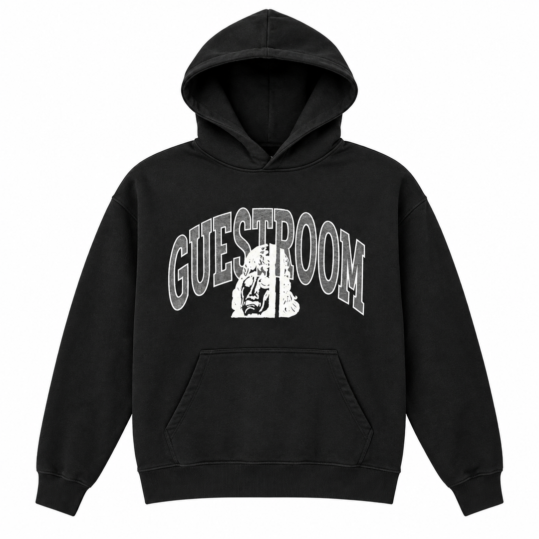 A black pullover hoodie with a white graphic print on the chest reading 'GUESTROOM' in arched varsity letters over a stylized face illustration, shown on a plain white background.