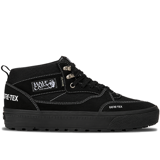 A black mid-top sneaker by Half Cab x Gore-Tex, featuring a canvas and suede upper, black laces, white contrast stitching, and a thick black sole with a rugged tread.
