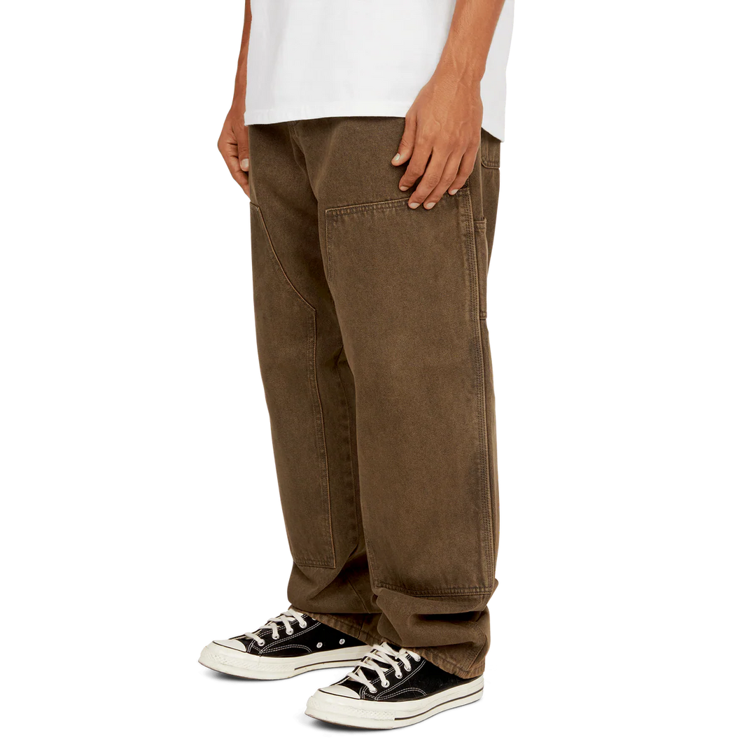 Person wearing brown pants and black sneakers on a white background