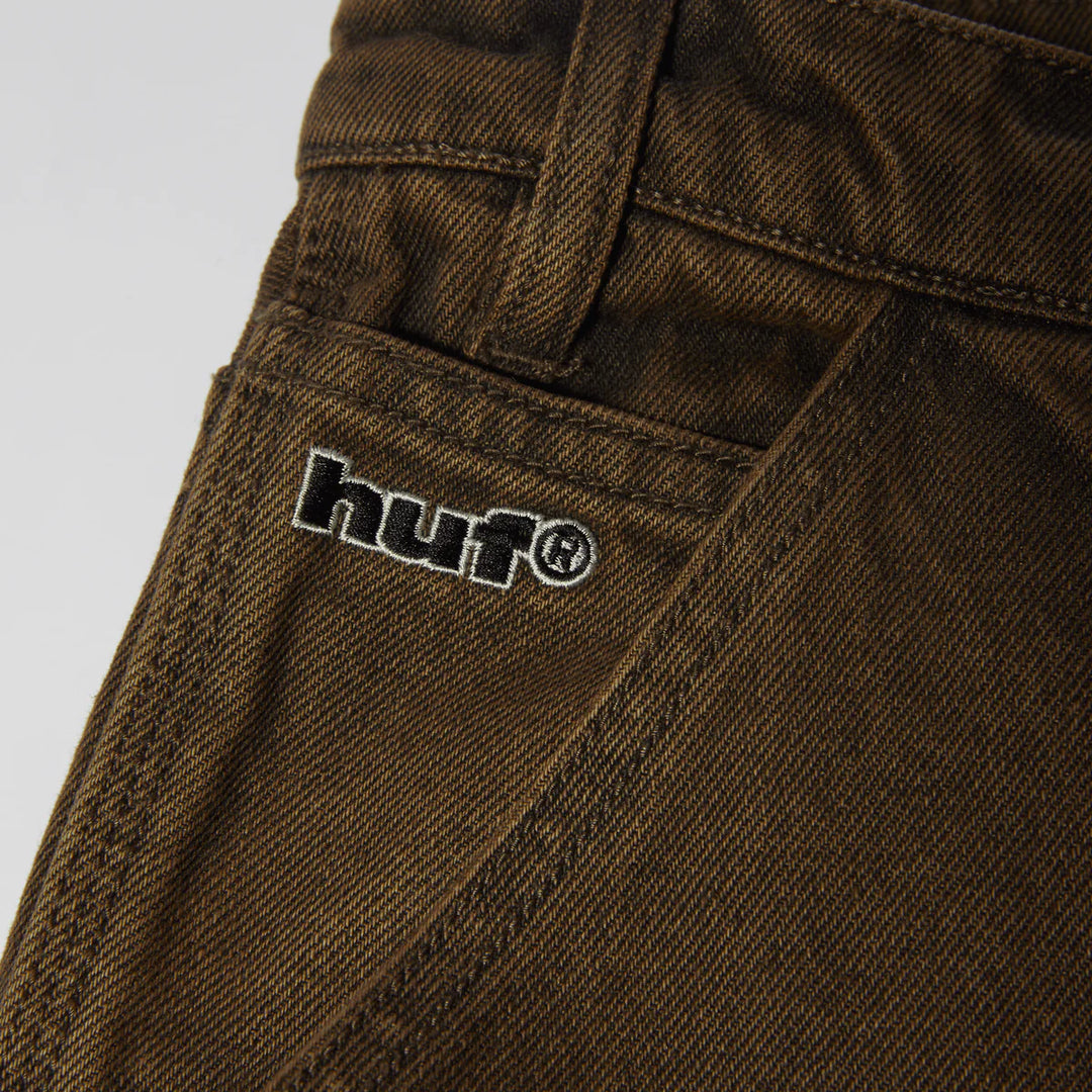Brown pants with a visible HUF brand logo on a light gray background