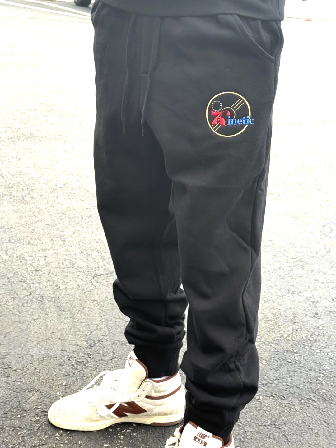 Black jogger pants with a logo on the leg, worn by a person
