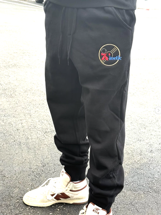 Black jogger pants with a logo on the leg, worn by a person