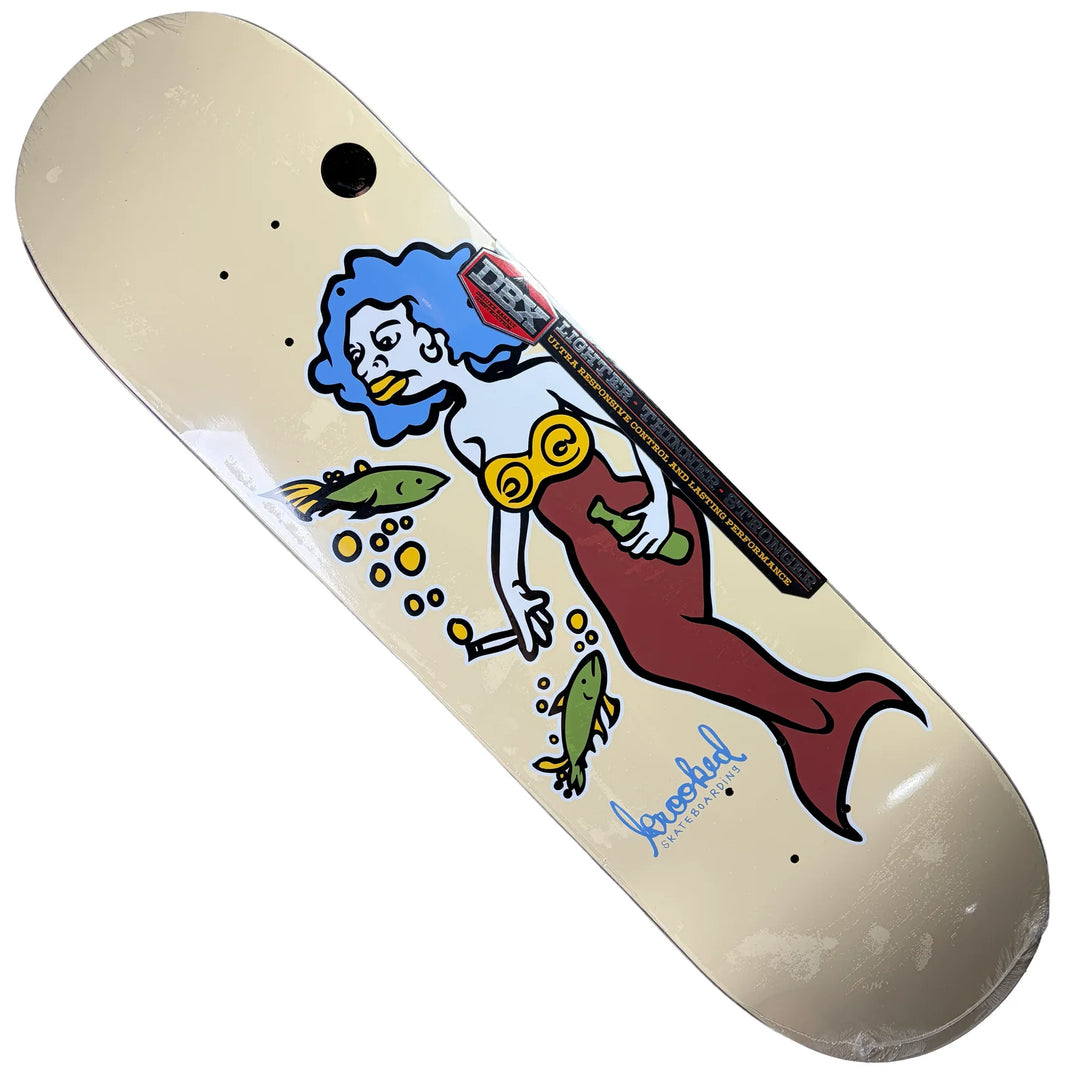 A skateboard deck with a cream-colored base, featuring a graphic illustration of a mermaid with blue hair, a red tail, and yellow goggles, alongside fish and bubbles. The brand name &