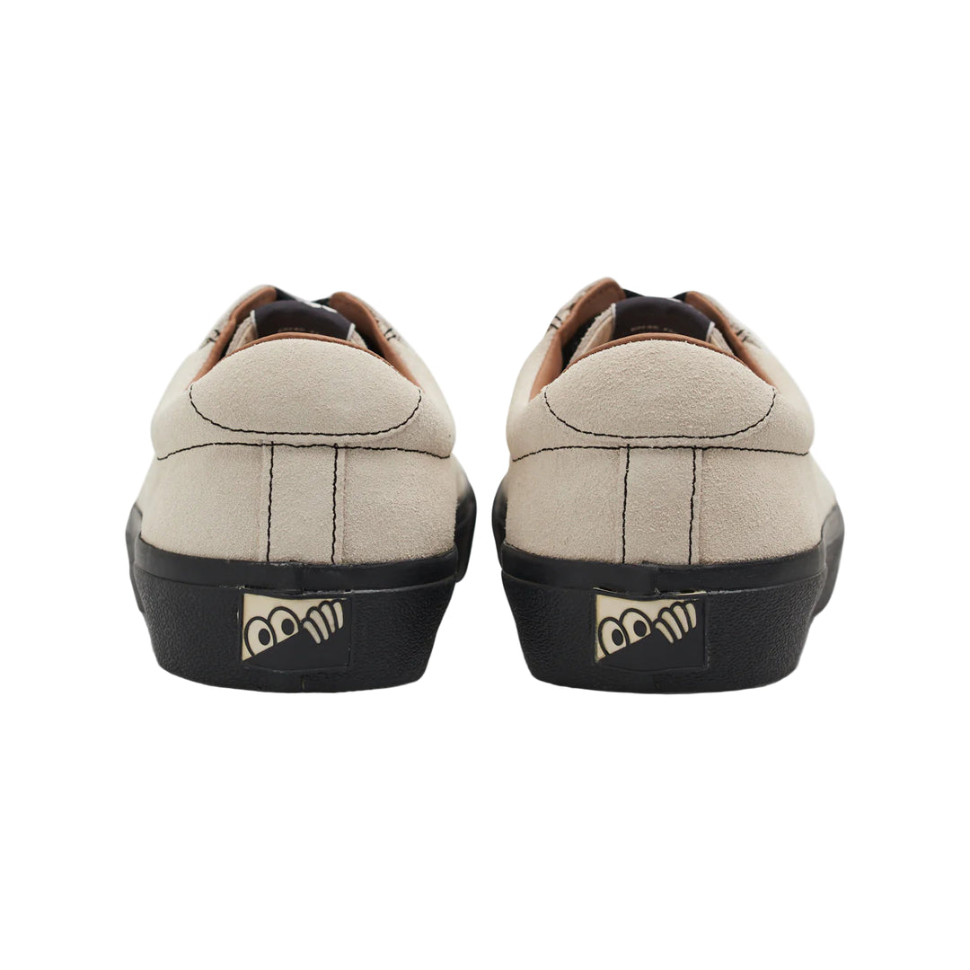 Pair of beige sneakers with black soles on a white background