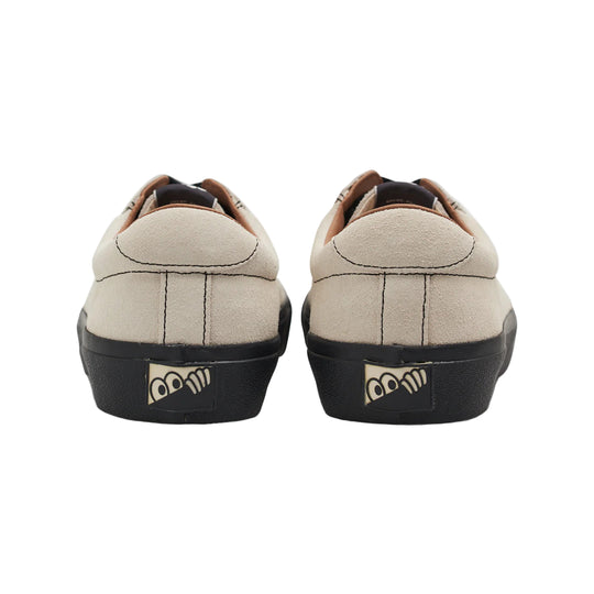 Pair of beige sneakers with black soles on a white background