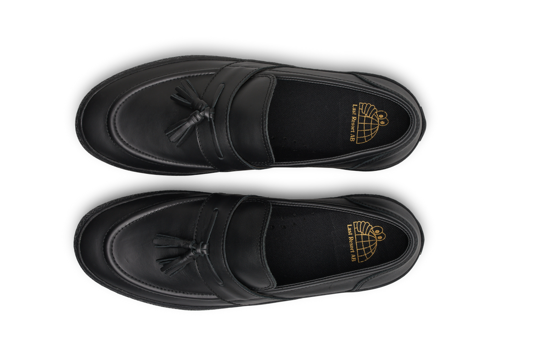 Black loafers with tassels on a white background