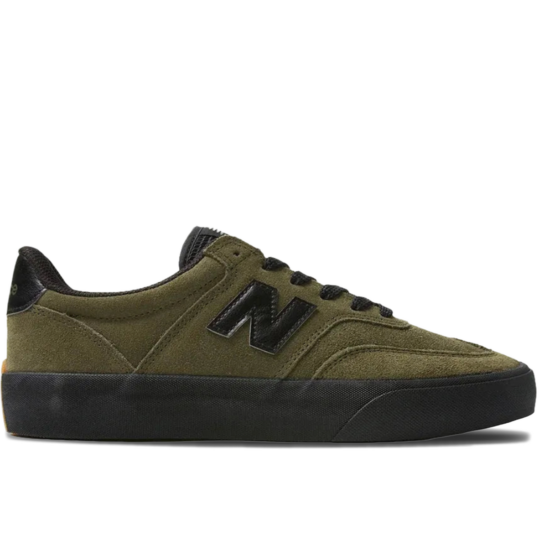 An olive green suede New Balance sneaker with black laces, a black heel tab, and a thick black rubber sole, shown in a side profile on a white background.