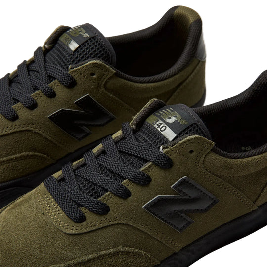 Close-up of a pair of New Balance 340 sneakers in olive green suede and black mesh, featuring black laces and the signature black &