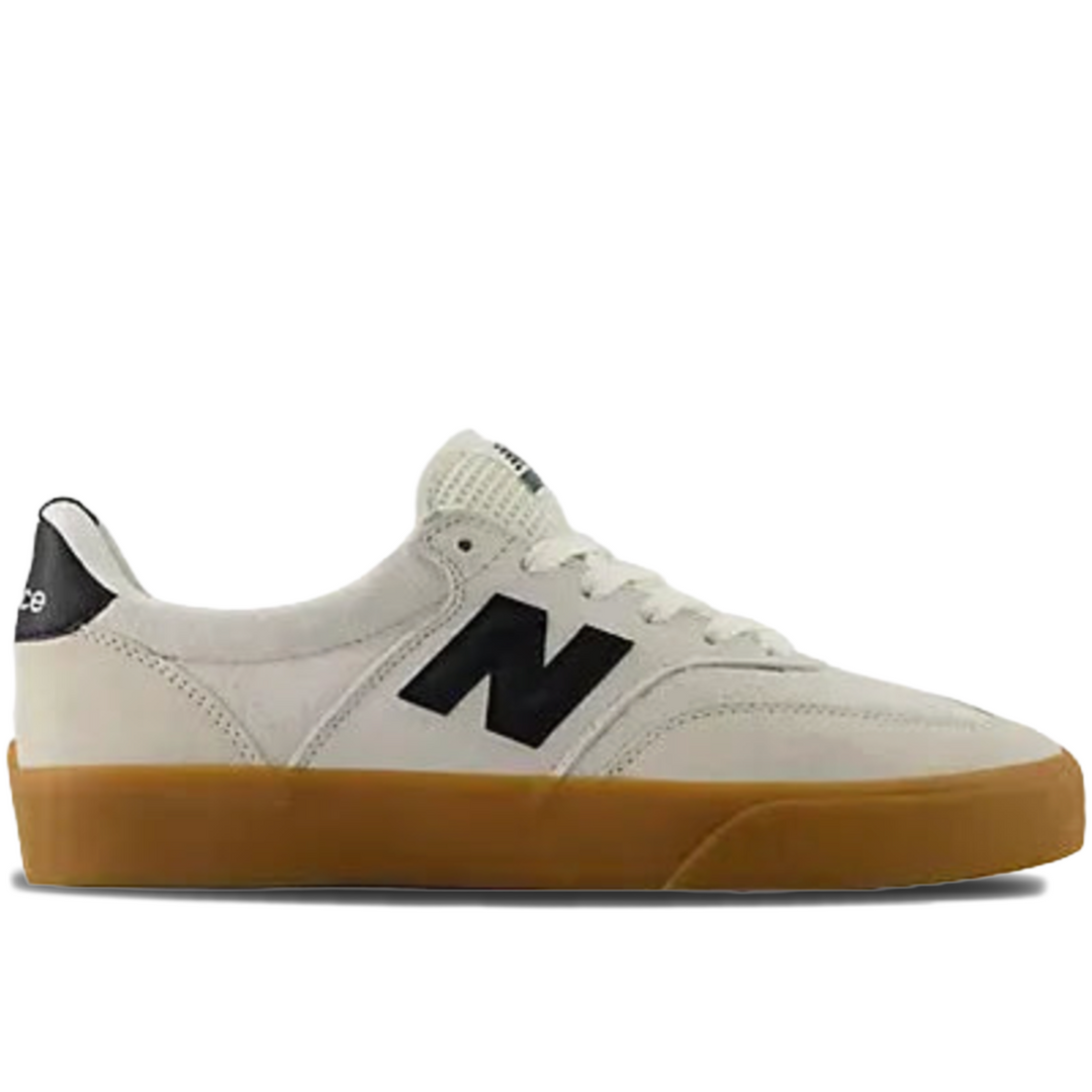 A New Balance low-top sneaker in off-white with a black 'N' logo, black heel tab, and a brown gum sole, shown from a side profile on a white background.