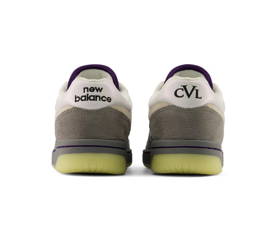 Two New Balance sneakers shown from the back, featuring a white and gray suede and mesh upper, a purple heel tab, and a translucent yellow-green outsole, on a white background.
