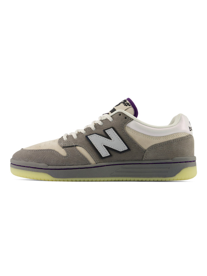 A New Balance sneaker in a muted taupe-gray and cream colorway, featuring a white &