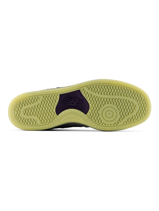 The outsole of a sneaker shown from a top-down view, featuring a light yellow-green gum rubber sole with a dark purple heel accent.