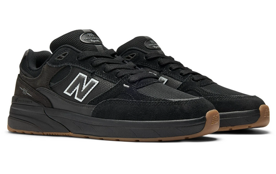 Black New Balance sneakers with brown soles oand a gum toe