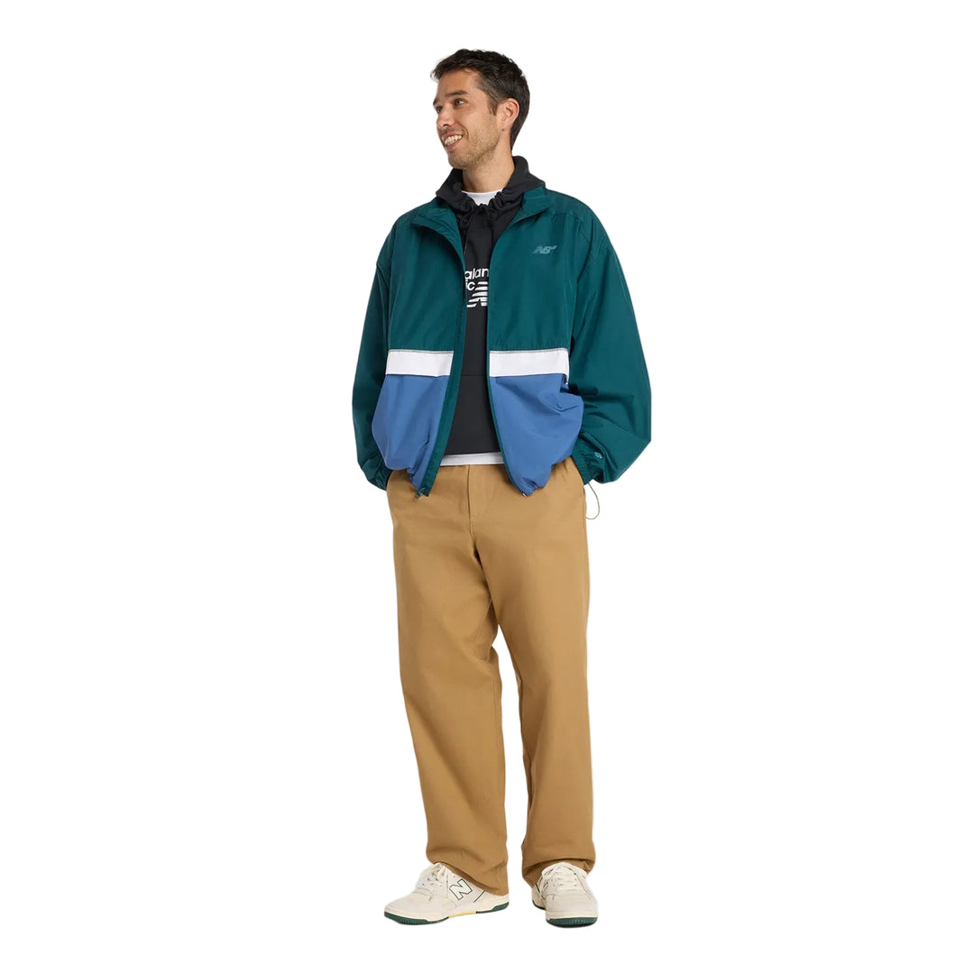 Skater wearing a green and blue jacket with beige pants 