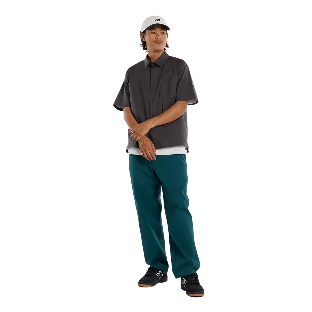 Skater wearing a dark shirt, teal pants, and a white cap 