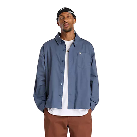 Man wearing a blue jacket, white shirt, and brown pants on a white background