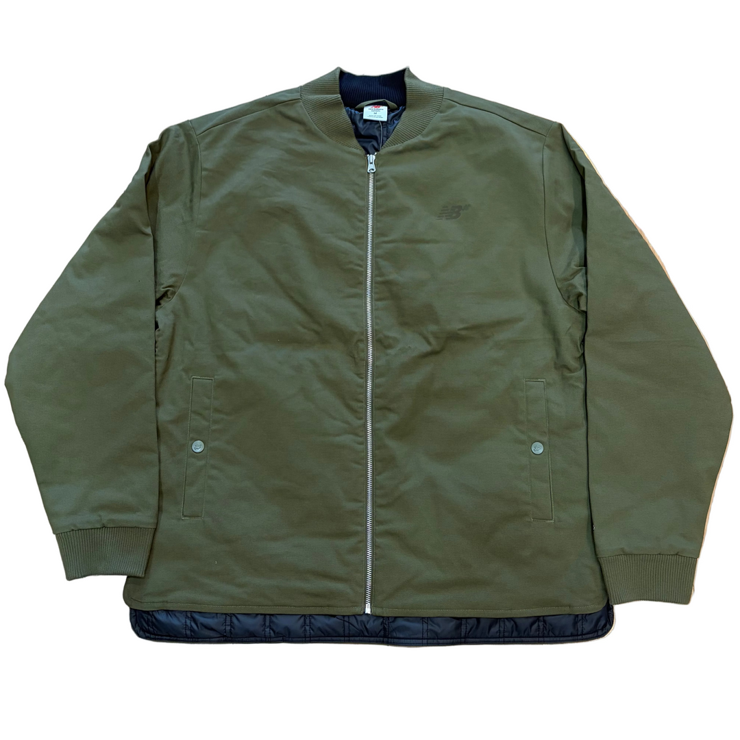 An olive green bomber jacket with a dark navy blue quilted lining visible at the collar, hem, and front opening, laid flat against a white background.