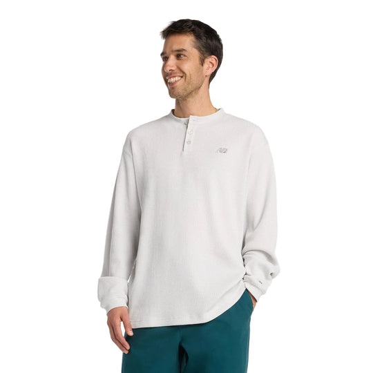 Man wearing a light gray long-sleeve shirt and teal pants