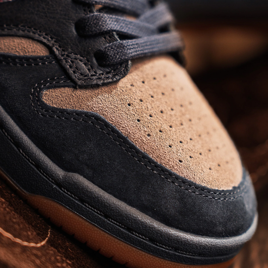 Close-up of a brown and black suede shoe with a blurred background