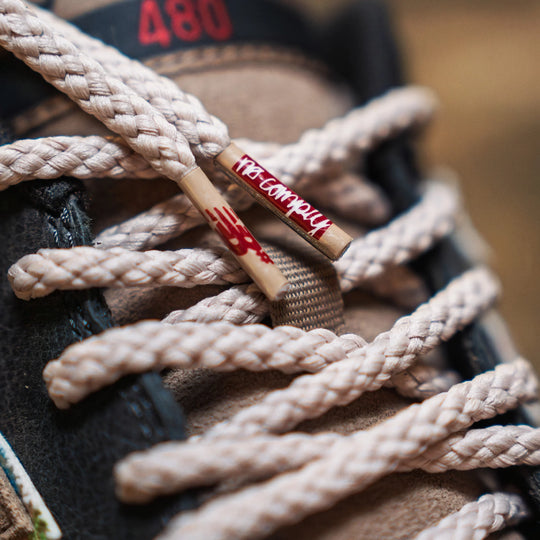 Close-up of beige shoelaces with a brand logo on a blurred background