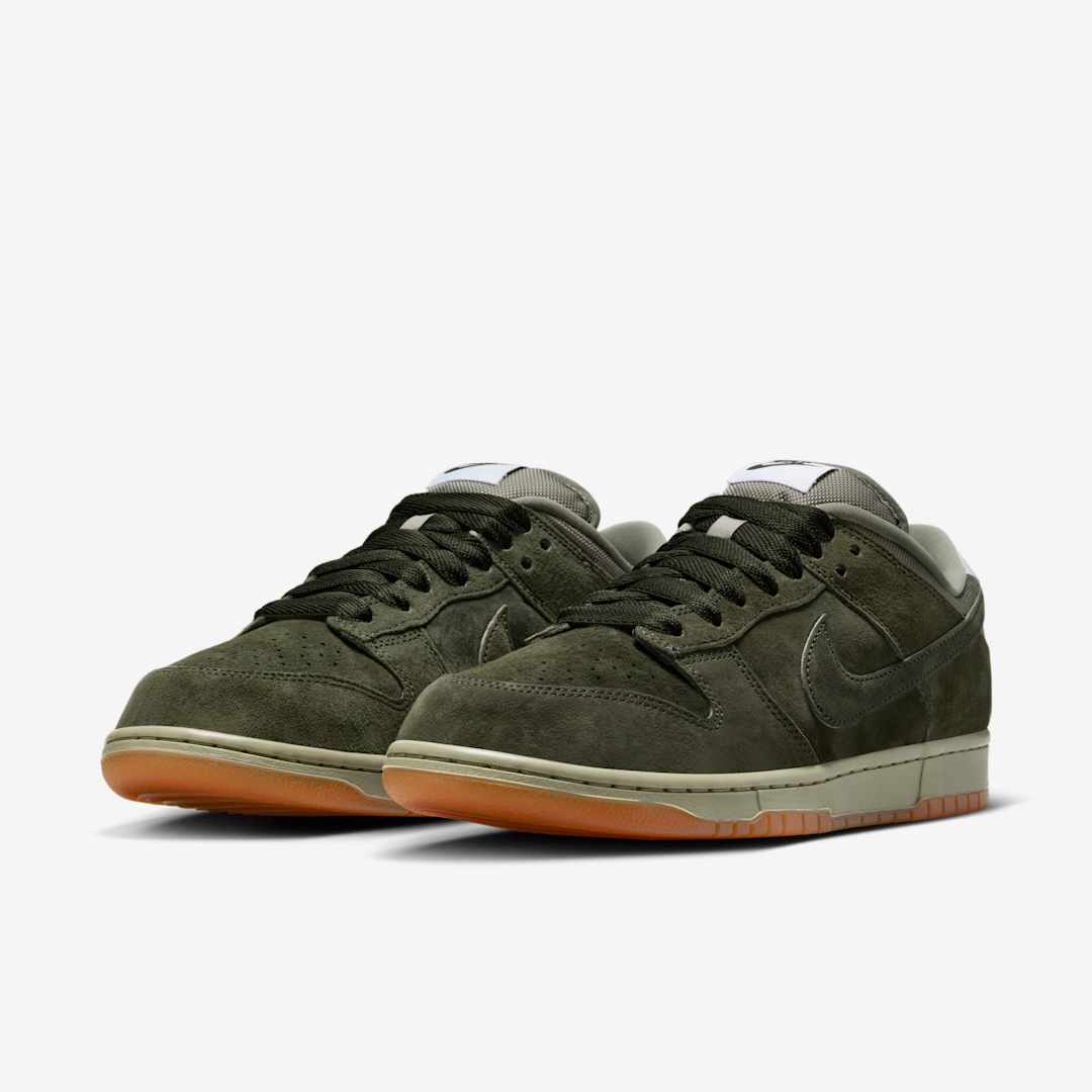 Pair of green suede sneakers with brown soles on a white background