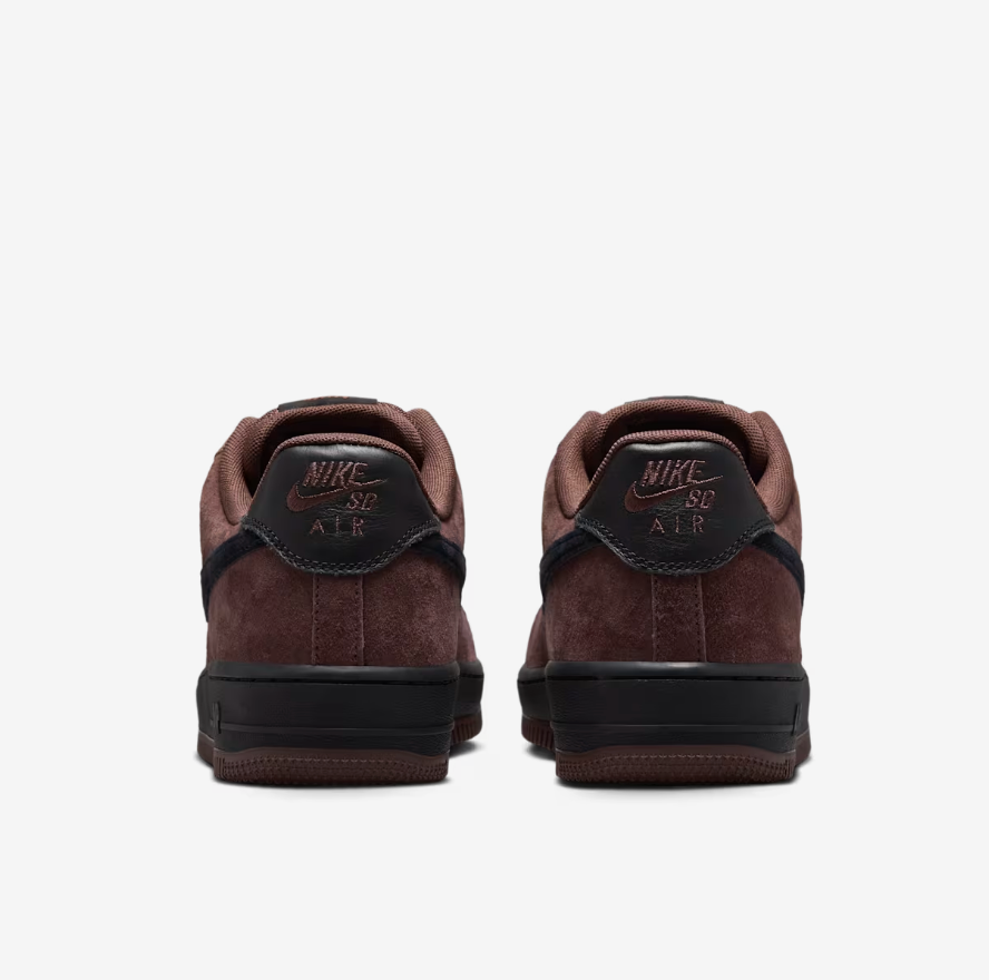 A pair of Nike Air Force 1 Low sneakers shown from the back, featuring dark brown suede and leather panels, a black heel tab with brown &