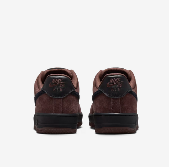 A pair of Nike Air Force 1 Low sneakers shown from the back, featuring dark brown suede and leather panels, a black heel tab with brown &