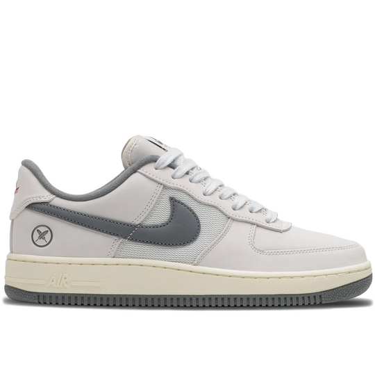 A Nike Air Force 1 Low sneaker in a light gray and off-white colorway, featuring a dark gray Swoosh and heel tab, a cream midsole, and a dark gray outsole.