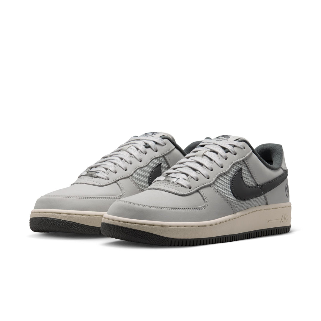 A pair of Nike Air Force 1 Low sneakers in light gray suede and mesh with dark gray Swooshes, beige midsoles, and black outsoles, shown on a white background.