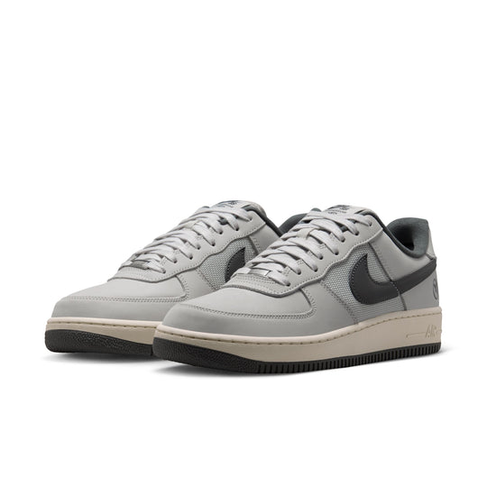 A pair of Nike Air Force 1 Low sneakers in light gray suede and mesh with dark gray Swooshes, beige midsoles, and black outsoles, shown on a white background.