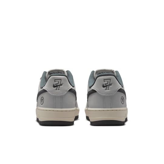 A pair of low-top sneakers shown from the back, featuring a light gray leather upper, dark gray overlays with a stylized &